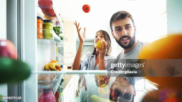 若いカップルは、いくつかの果物や冷蔵庫から野菜を拾います。 - kitchen pantry ストックフォトと画像