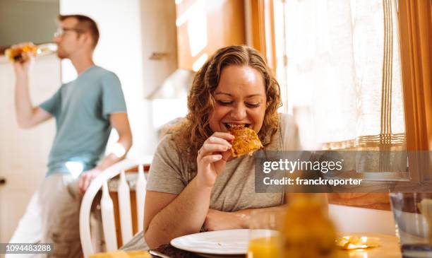 groot formaat vrouw eet pizza thuis - funny fat women stockfoto's en -beelden