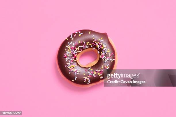 overhead view of chocolate donut with sprinkles on pink background - hundreds and thousands stock pictures, royalty-free photos & images
