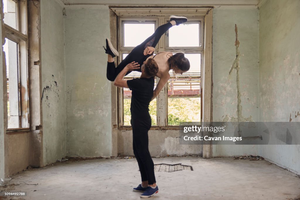 Man lifting ballerina while dancing in old building