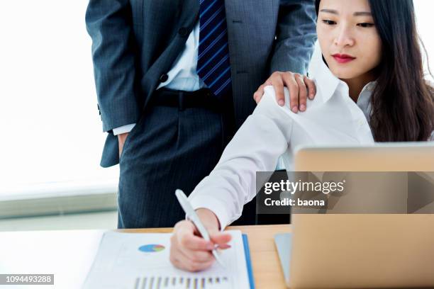 man looking over the shoulder at his female colleague work - harassment work stock pictures, royalty-free photos & images