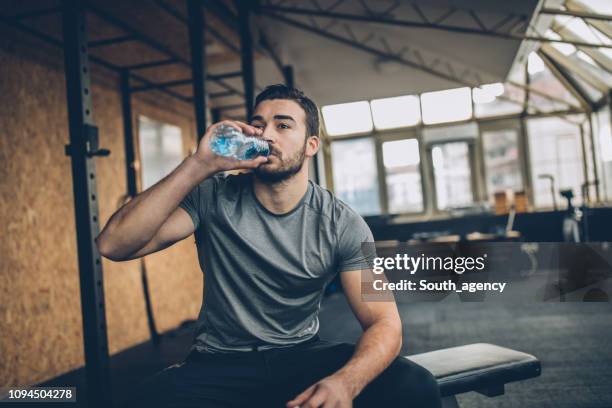 mann trinkwasser nach dem training im fitness-studio - sport drinking bottle stock-fotos und bilder