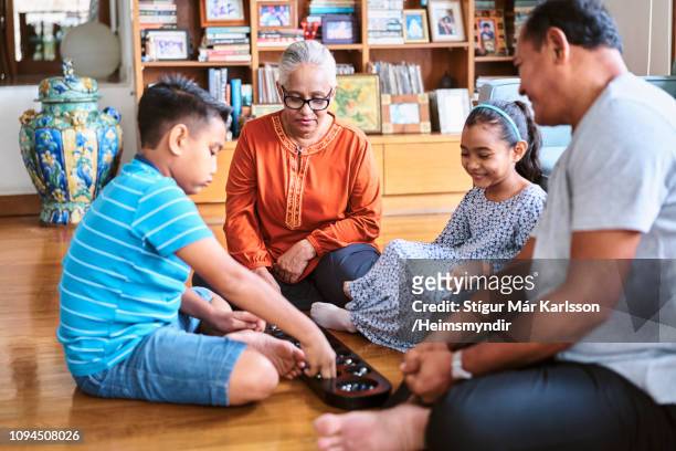 grandparents playing wari board game with kids - wari imagens e fotografias de stock