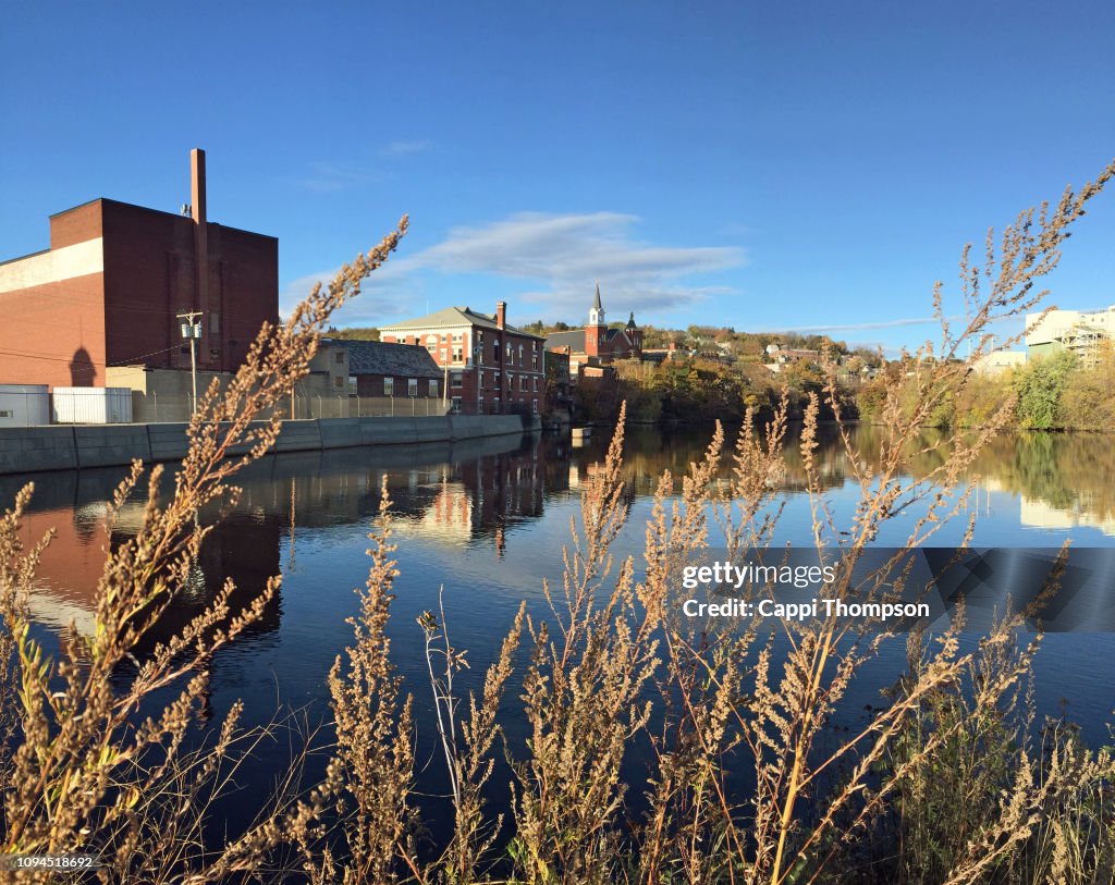 Mason Street Bridge view in Berlin, New Hampshire USA looking up the Androscoggin River with building and chruches