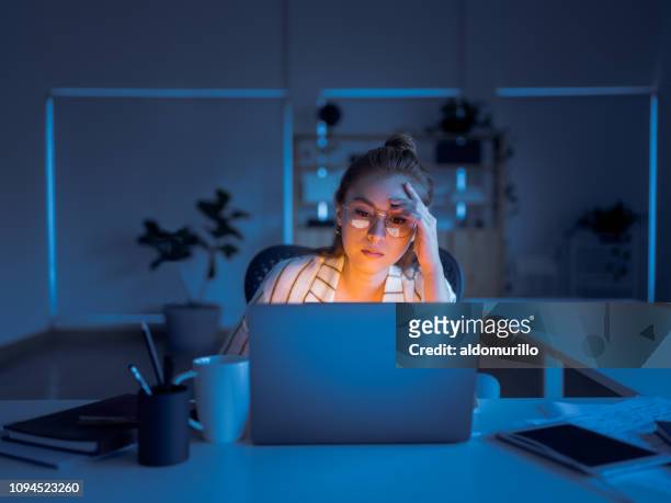 young woman working late in office - beautiful woman and tired stock pictures, royalty-free photos & images
