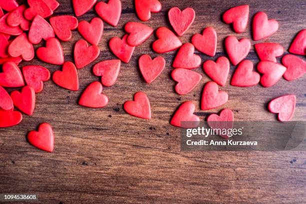 valentines day background with red hearts on a wooden table, top view. red heart shaped candies on a wooden brown background. the concept of valentines day. - february background stock pictures, royalty-free photos & images