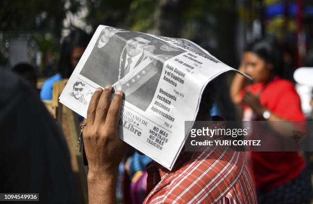 Man protects himself from the sun with a newspaper featuring Venezuelan President Nicolas Maduro on its cover, at Bolivar square in Caracas during a...