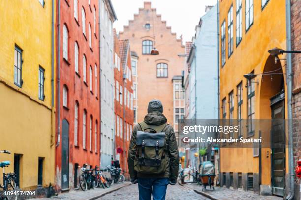young man with backpack walking in the streets of copenhagen old town - escapade urbaine photos et images de collection