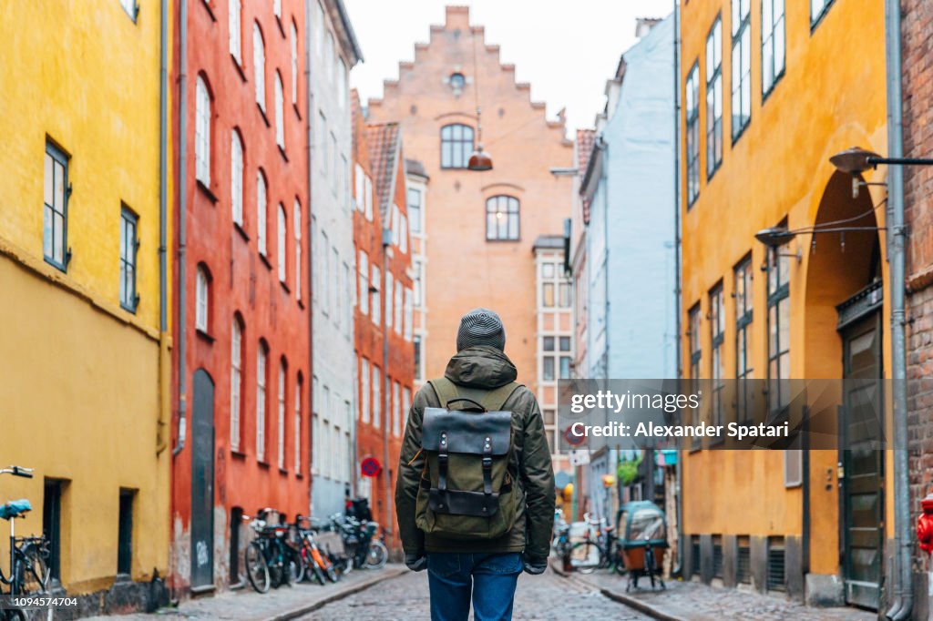 Young man with backpack walking in the streets of Copenhagen old town