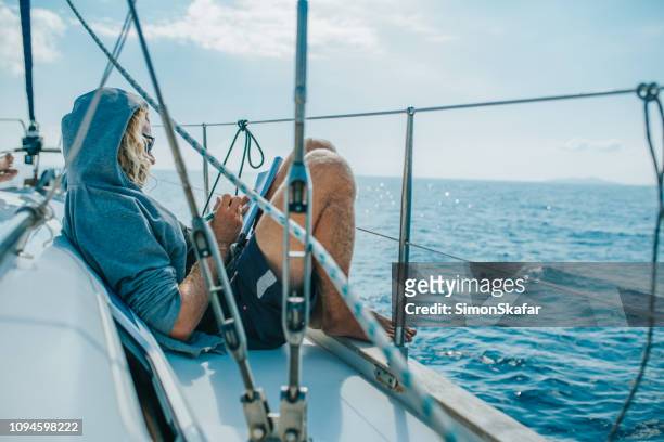 man solving crossword puzzle on sailing boat - crossword puzzle stock pictures, royalty-free photos & images