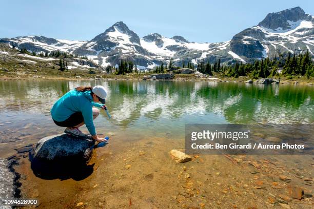 woman filling bottle with water from lake,pemberton, british columbia, canada - 浄水 ストックフォトと画像