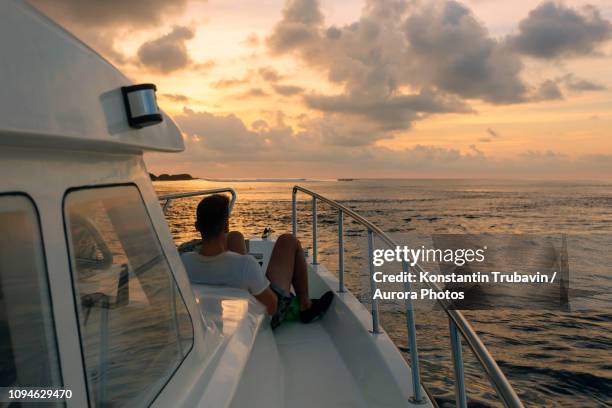 man on sailboat at sunset, thulusdhoo, male, maldives - male maldives ストックフォトと画像