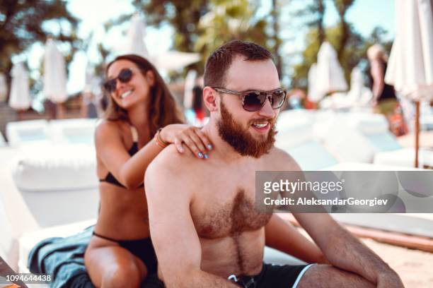 adorable girl giving a beach massage to her boyfriend - massage funny stock pictures, royalty-free photos & images