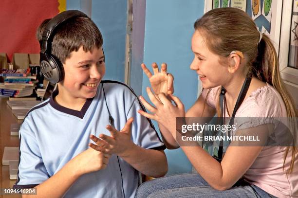 deaf children with hearing aids in a school class room using sign language - sign language fotografías e imágenes de stock