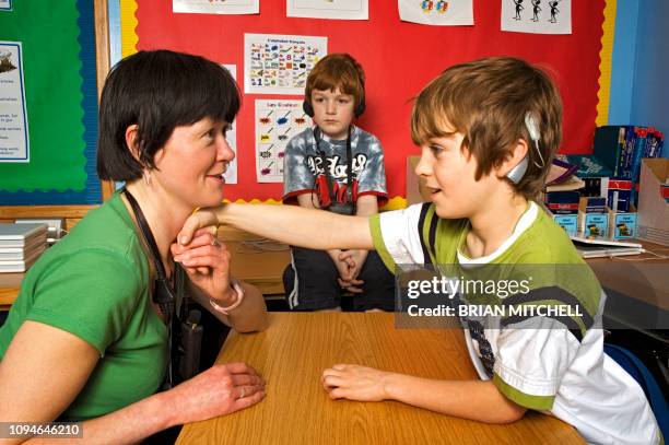 deaf children with hearing aids in a school class room using sign language - prosthetic equipment stock pictures, royalty-free photos & images