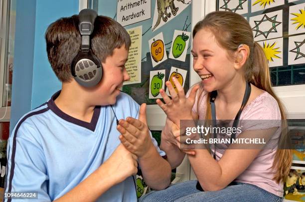 deaf children with hearing aids in a school class room using sign language - sign language stock pictures, royalty-free photos & images