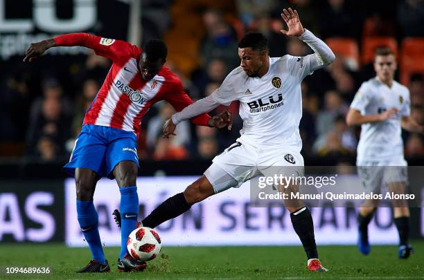 Francis Coquelin of Valencia CF competes for the ball with Isaac Cofie of Sporting Gijon during the Copa del Rey Round of 16 second leg match between...