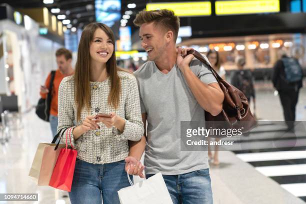 couple of travelers at the airport shopping at the duty free - couple traveler stock pictures, royalty-free photos & images