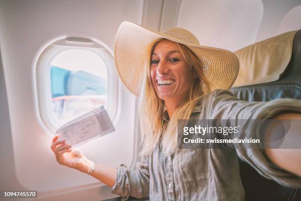 young woman in airplane takes mobile phone selfie portrait during flight - commercial airplane stock pictures, royalty-free photos & images