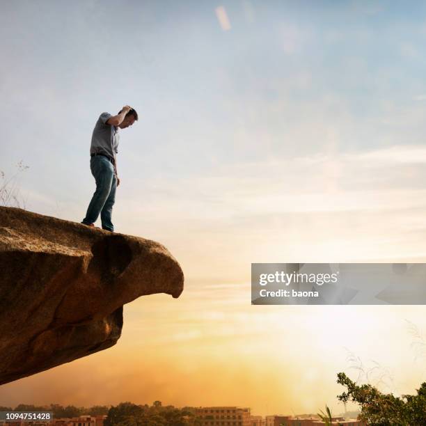 man staat aan de rand van een klif en denken - hoogtevrees stockfoto's en -beelden