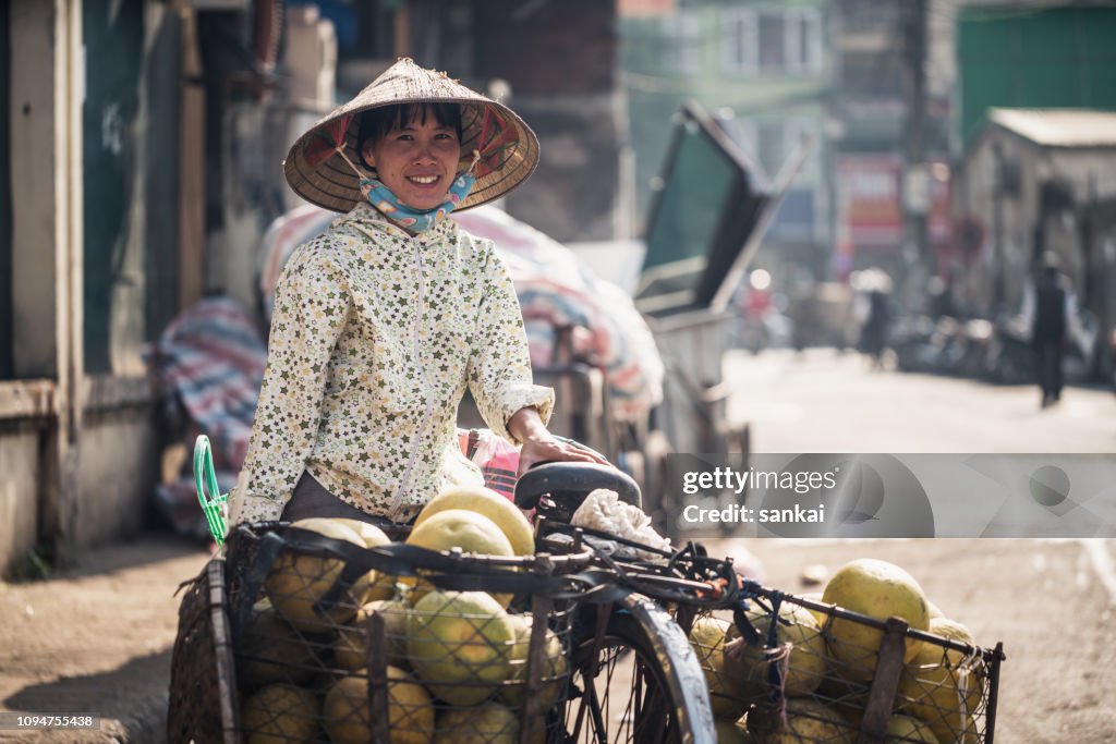 Portrait of Vietnamese woman selling tropical fruits on the street of Hanoi city, Vietnam