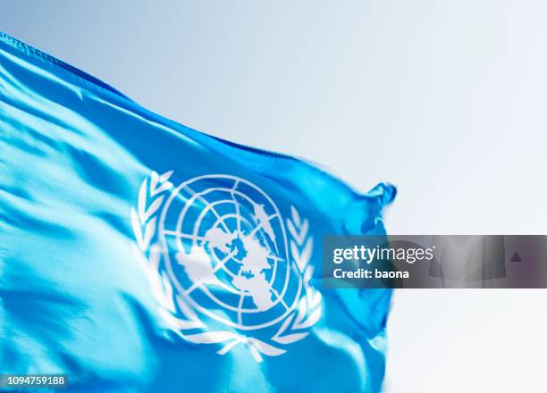 united nations flag waving in the wind - international law stock pictures, royalty-free photos & images