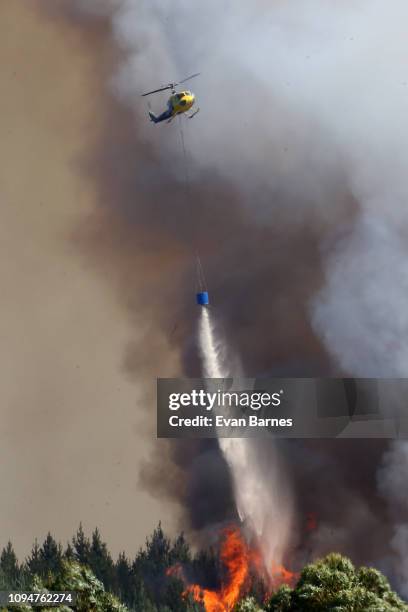 New Zealand Helicopters dump water to extinguish the blaze as 170 homes have been evacuated from the area in the Tasman district February 7, 2019 in...