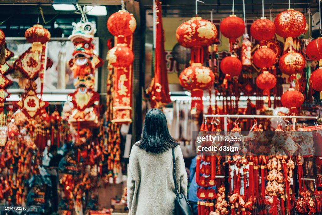 Rear view of woman standing against various Chinese New Year decorations and ornaments on city street