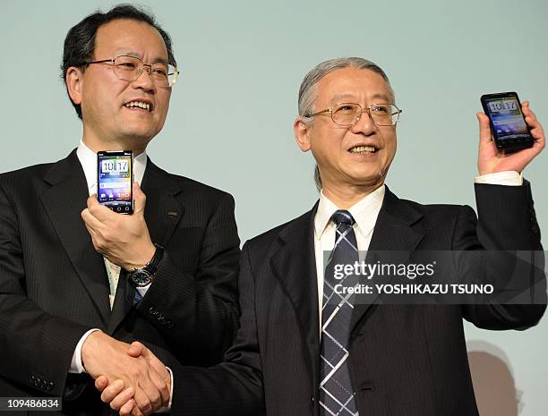 Japan's telecommunication giant KDDI president Takashi Tanaka shakes hands with Taiwan's electronics giant HTC executive vice president Fred Liu as...
