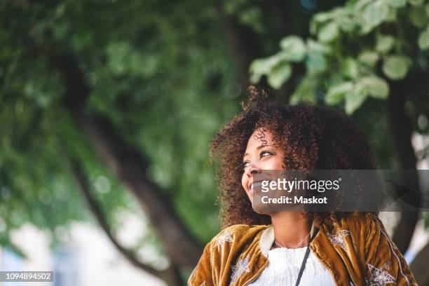 close-up of thoughtful mid adult woman with curly hair looking away at park - contemplation outside bildbanksfoton och bilder