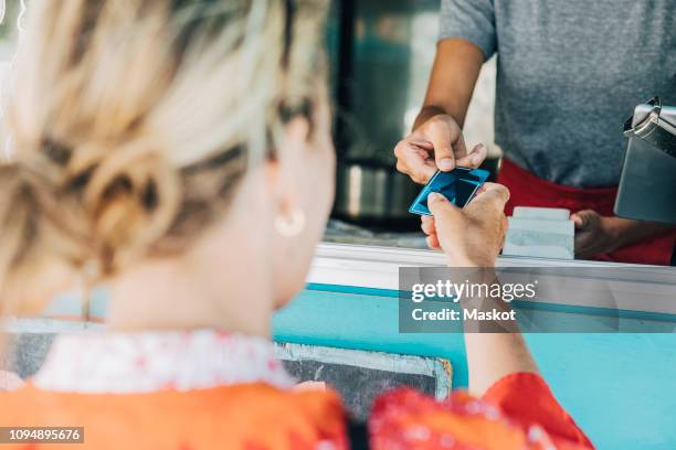 rear view of female customer giving credit card to owner standing in food truck - handing over credit card stock pictures, royalty-free photos & images