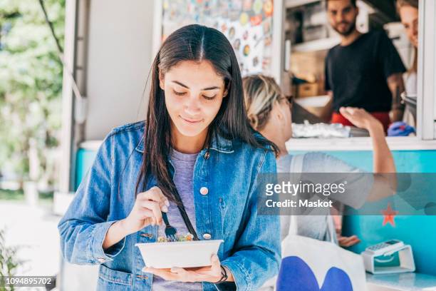 young woman eating fresh tex-mex in bowl against food truck - food stall stock pictures, royalty-free photos & images