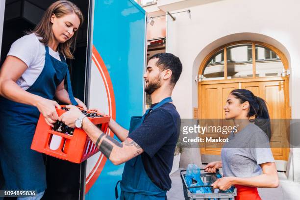 multi-ethnic colleagues holding crates while loading food truck in city - outdoor concession stand stock pictures, royalty-free photos & images