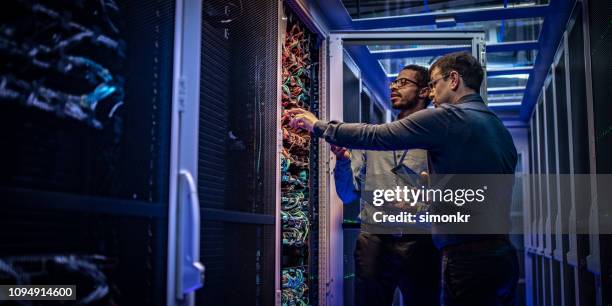 ingenieros servidores control en sala de servidores - datacenter fotografías e imágenes de stock