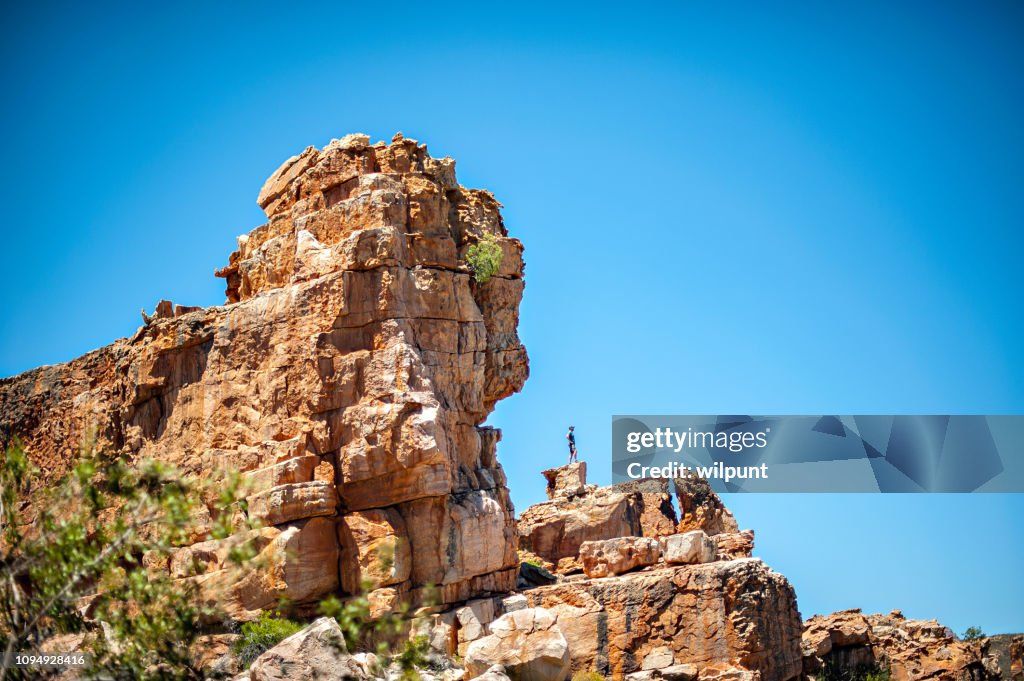 Man looking out from distant rock