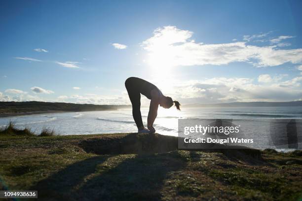 silhouette of fitness woman exercising on atlantic coastline. - 前屈運動 ストックフォトと画像