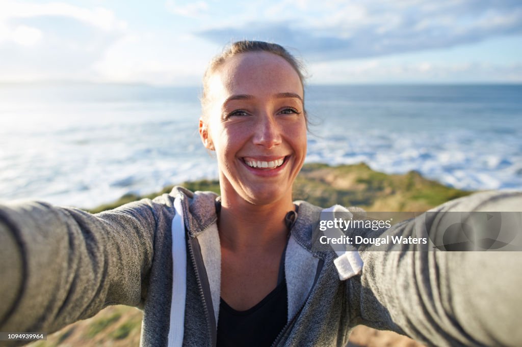 Woman in sportswear taking selfie beside sea.