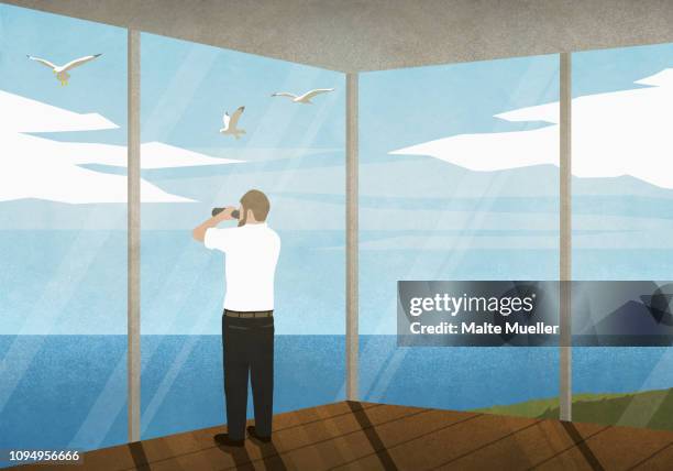 man with binoculars enjoying ocean view from beach house - fernglas stock-grafiken, -clipart, -cartoons und -symbole