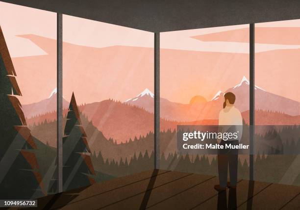 man enjoying tranquil view of sunset behind mountains from glass house - hands in pockets stock illustrations