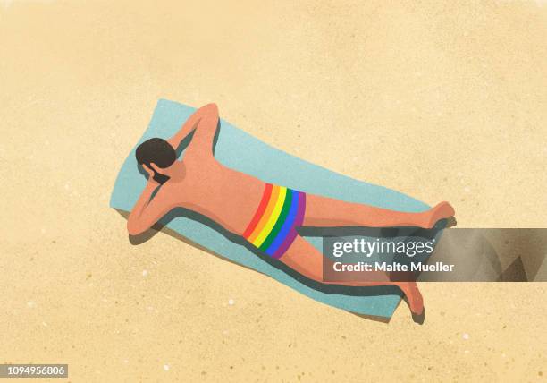 man in rainbow swim trunks sunbathing on beach - gay men stock illustrations