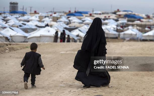 Displaced Syrian woman and a child walk toward tents at the Internally Displaced Persons camp of al-Hol in al-Hasakeh governorate in northeastern...