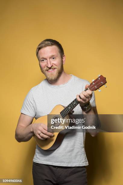 portrait smiling man playing ukulele - ukulele stock-fotos und bilder