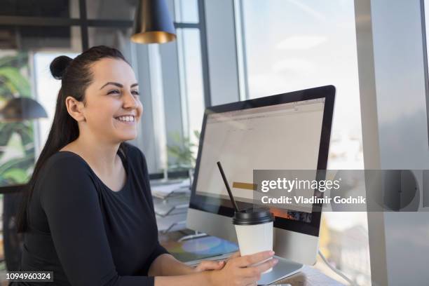 smiling woman drinking coffee and using computer at internet cafe - internetcafé bildbanksfoton och bilder