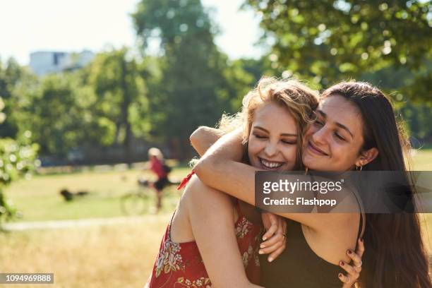 two young women embracing each other lovingly - embracing stock pictures, royalty-free photos & images