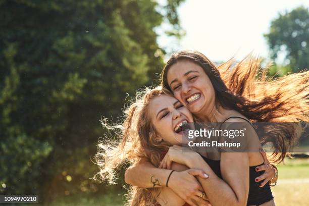 two young women embracing each other lovingly - die besten im fruehling stock-fotos und bilder