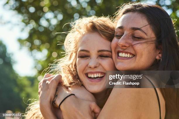 two young women embracing each other lovingly - affectionate stock pictures, royalty-free photos & images
