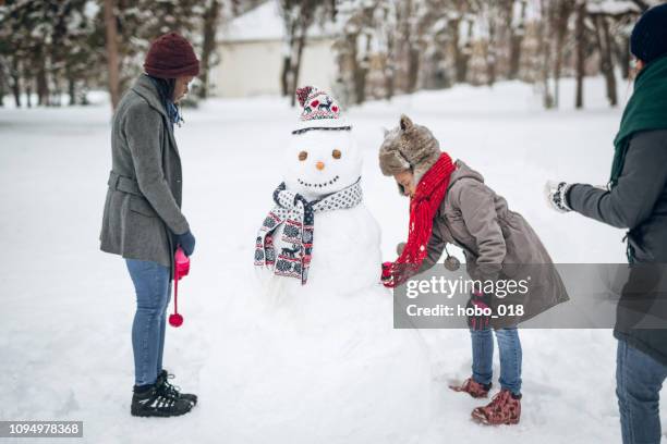 making snowman with friends and family - making a snowman stock pictures, royalty-free photos & images