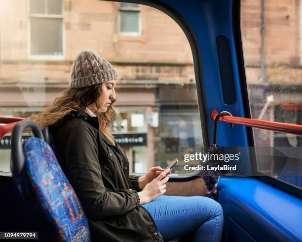 her phone keeps her company in transit - bus interior stock pictures, royalty-free photos & images