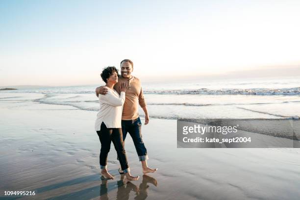 年配の男性がビーチで年配の女性と歩いて - couple travel middle age ストックフォトと画像