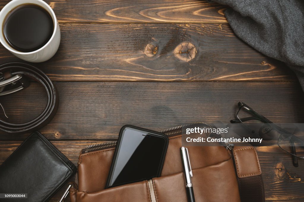Men's Satchel Bags, Mobile Phone and Male Personal Belongings on Rustic Wood